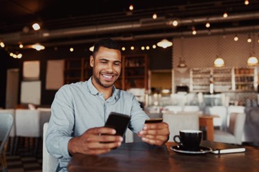 Man smiling at phone in a cafe