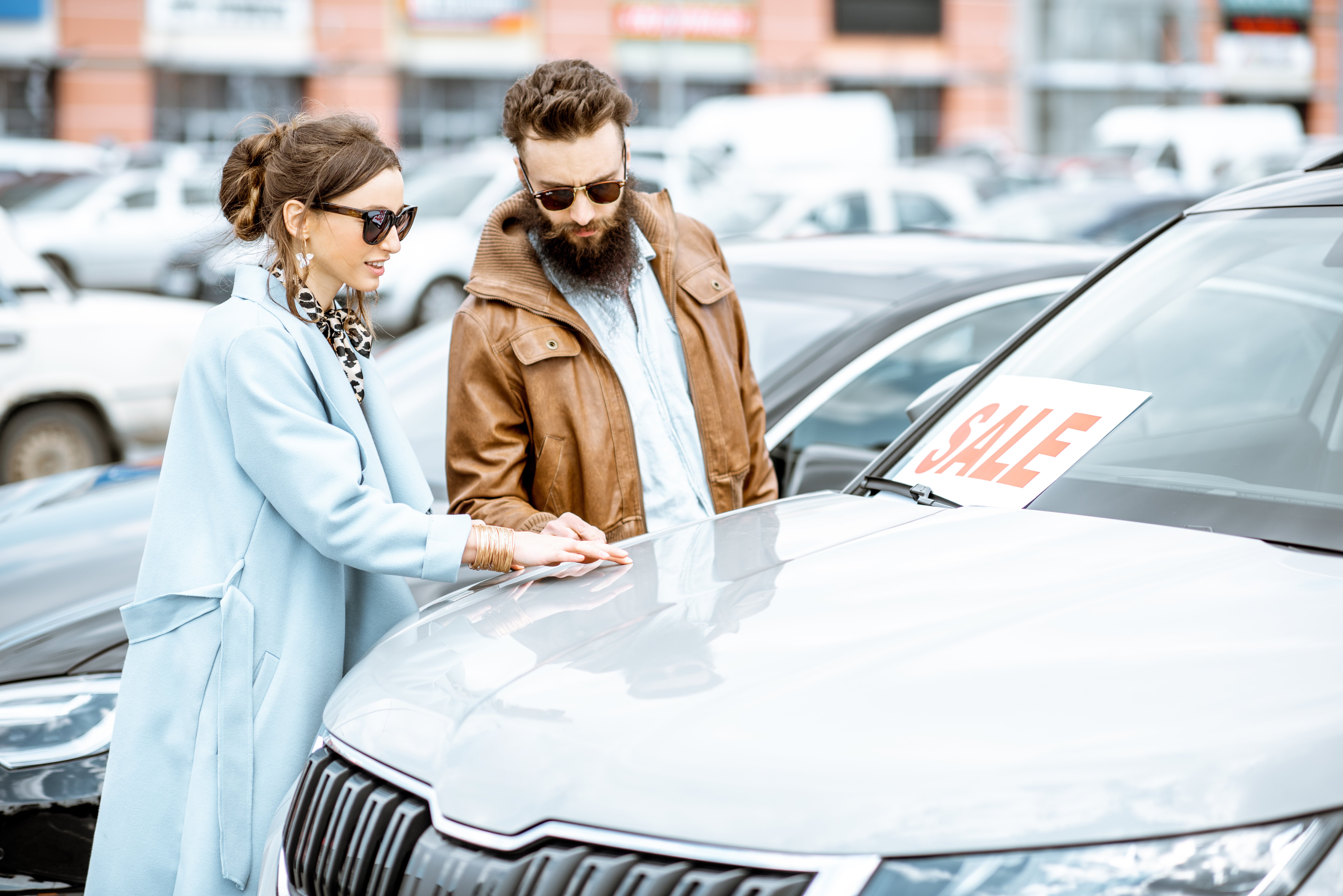Young stylish couple looking at used cars at a dealership