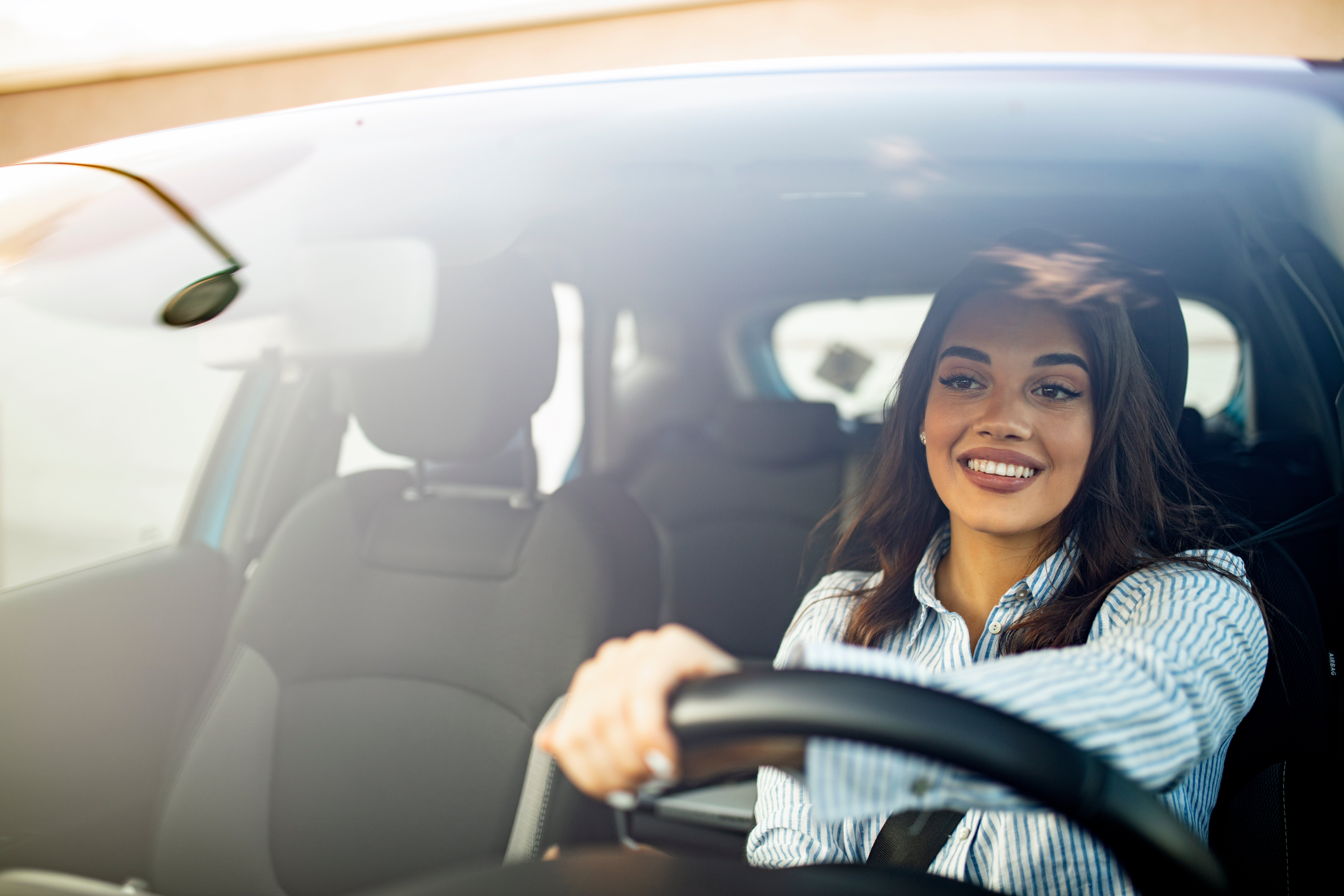 Young woman smiling while driving her new car