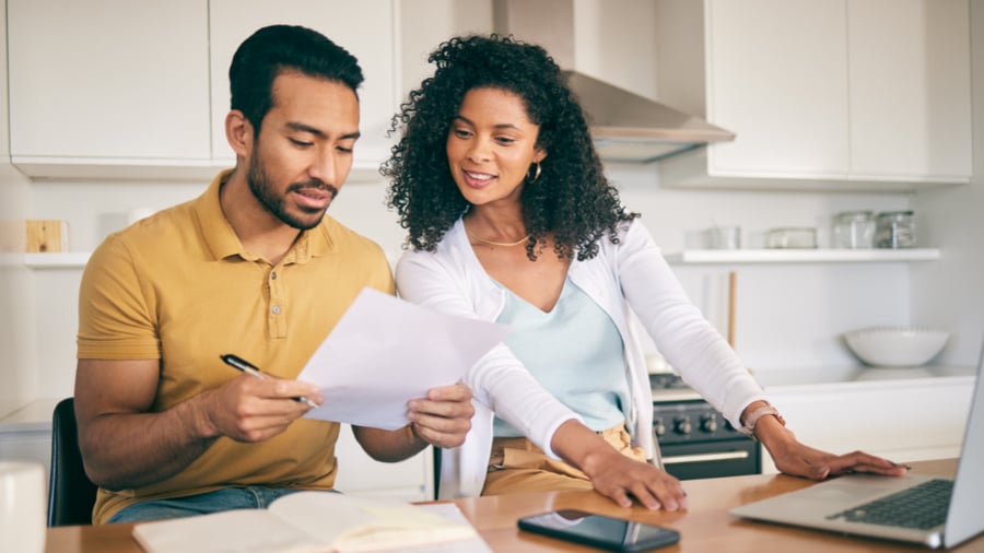 African couple sitting at the table with a laptop, discussing what to handle first to financially get back on track with their tax refund. 