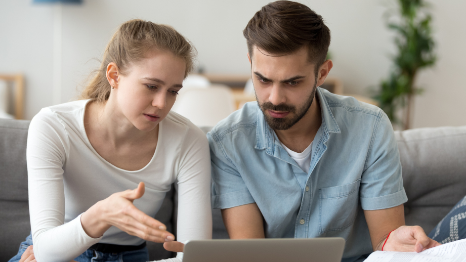 Two people focused on a computer, showing concern while navigating the homebuying process.