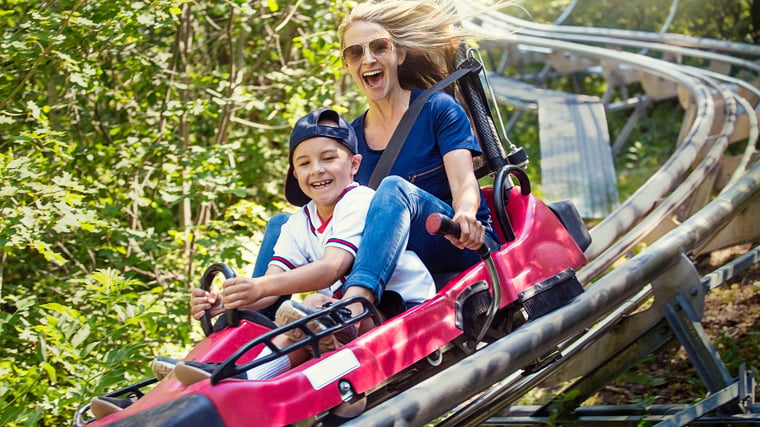 Mother and son riding a roller coaster in the summer time 