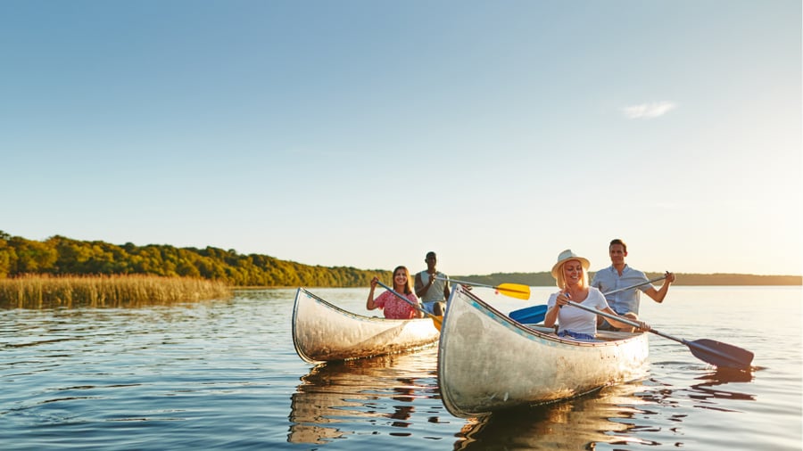 Two adult couples in different canoes, enjoying time outdoors
