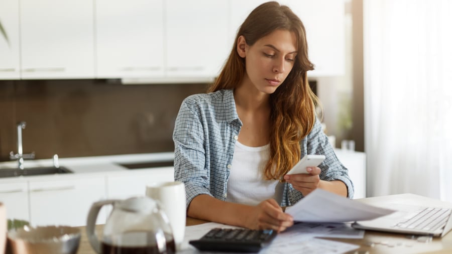 Woman looking through paperwork and her computer to decide if a personal loan is the right decision