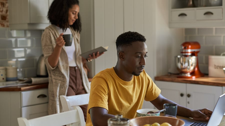 Woman and Man in the kitchen doing research on their computer, to make financial plans 