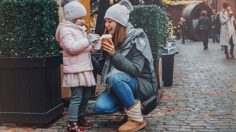 Young girl and mother are at a public place during the holiday season enjoying hot cocoa together and very happy