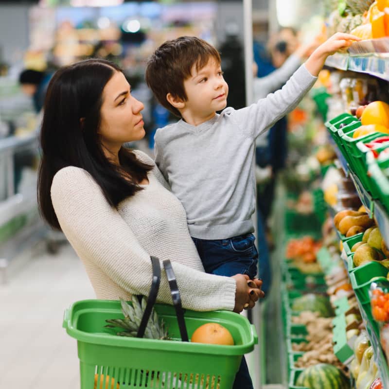 A young mother at the supermarket with her little baby boy. She is happy to use everyday spending to boost her credit and supply the needs of herself and her family.