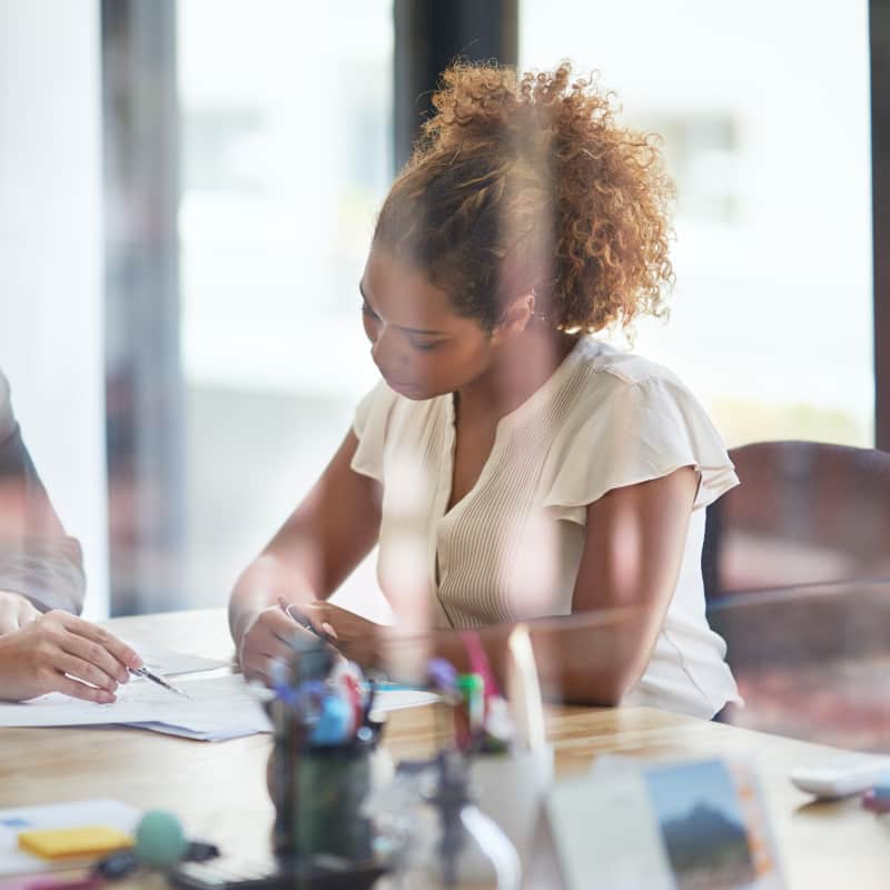 A financial advisor is meeting with a female client in an office to provide financial services and personal loan advice.
