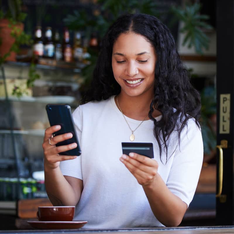 Woman, using her smartphone to make a credit card purchase for her business. She is happy to use her card with ease.