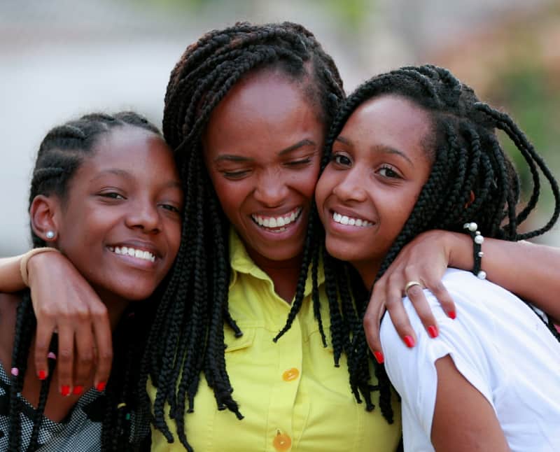 A Happy mother hugging her two daughters, enjoying financial peace of mind while spending time together.