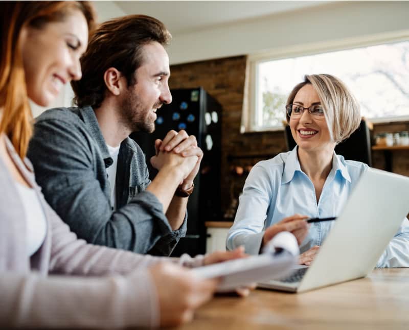 A happy financial advisor is talking to a couple during a meeting to discuss retirement planning. They are excited as they plan for a secure future.