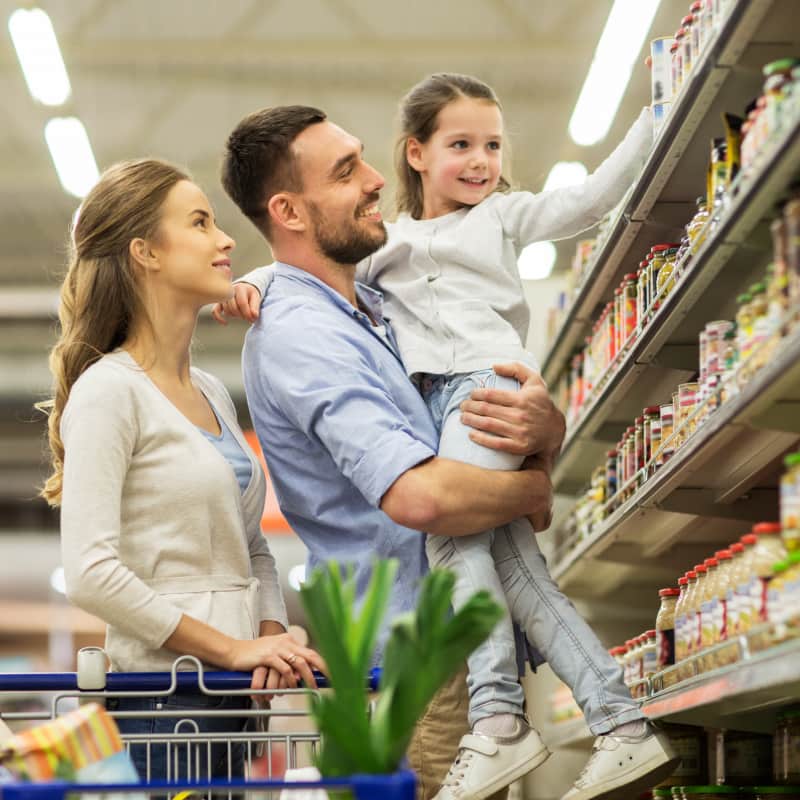 Mother and Father with their daughter, shopping at the supermarket. The family is happy and being rewarded for their everyday spending.