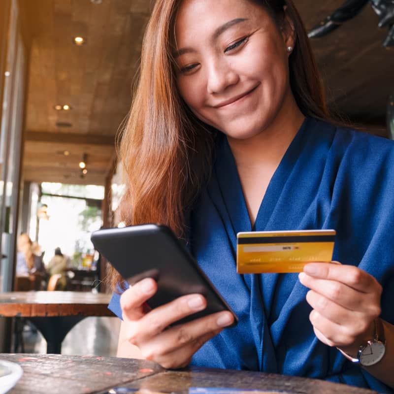 Happy woman at a cafe, paying for her items with her card.