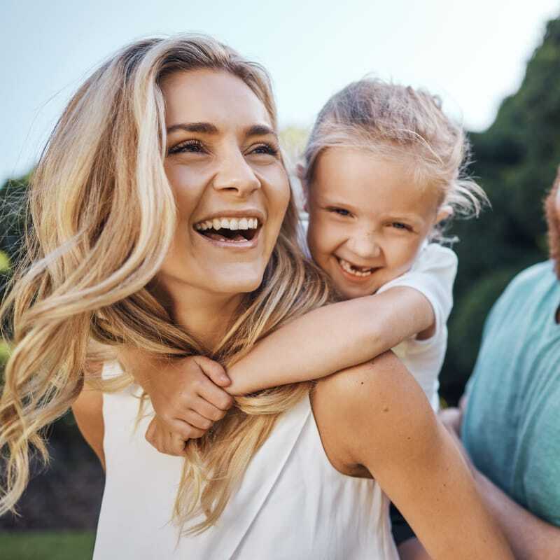 Family of three outdoors, happy and enjoying the summer with financial peace of mind