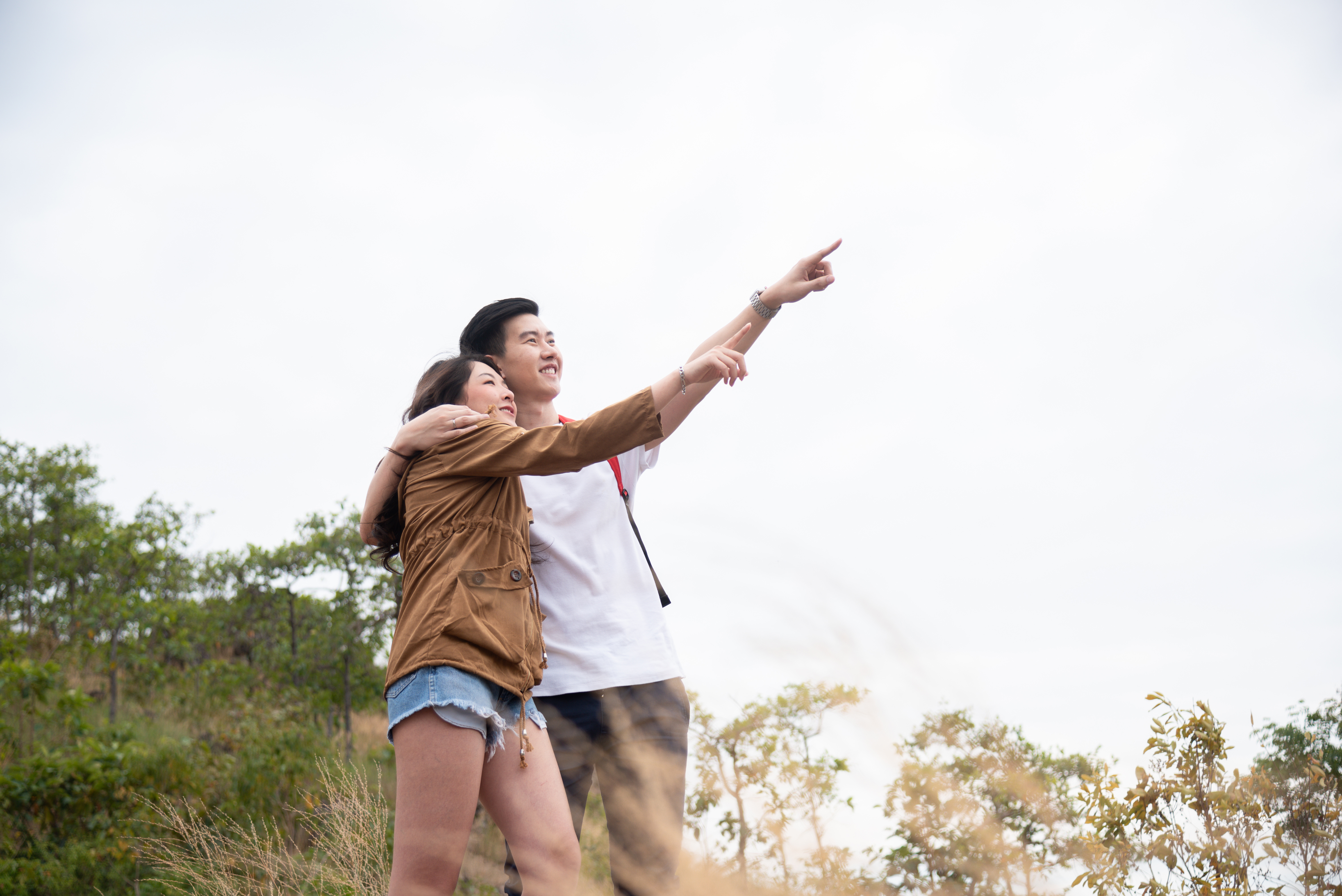 A young couple enjoys the scenery from a mountain overlook.